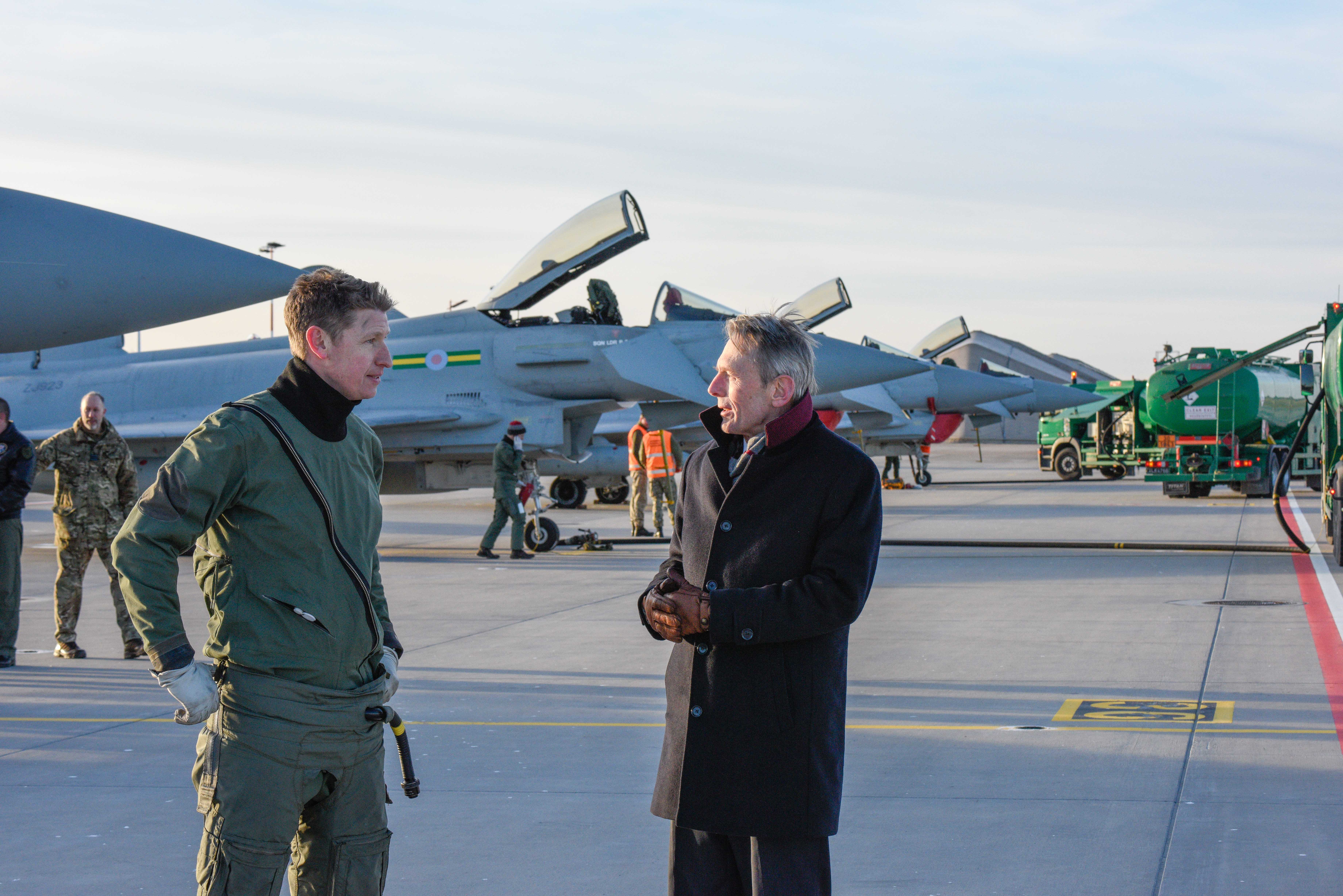 Pilots talk to each other on airfield, with Typhoons behind them.